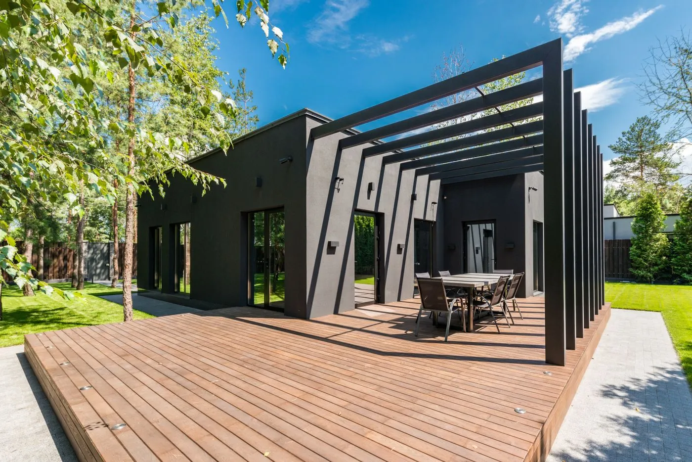 A wood deck with an outdoor dining set surrounded by greenery