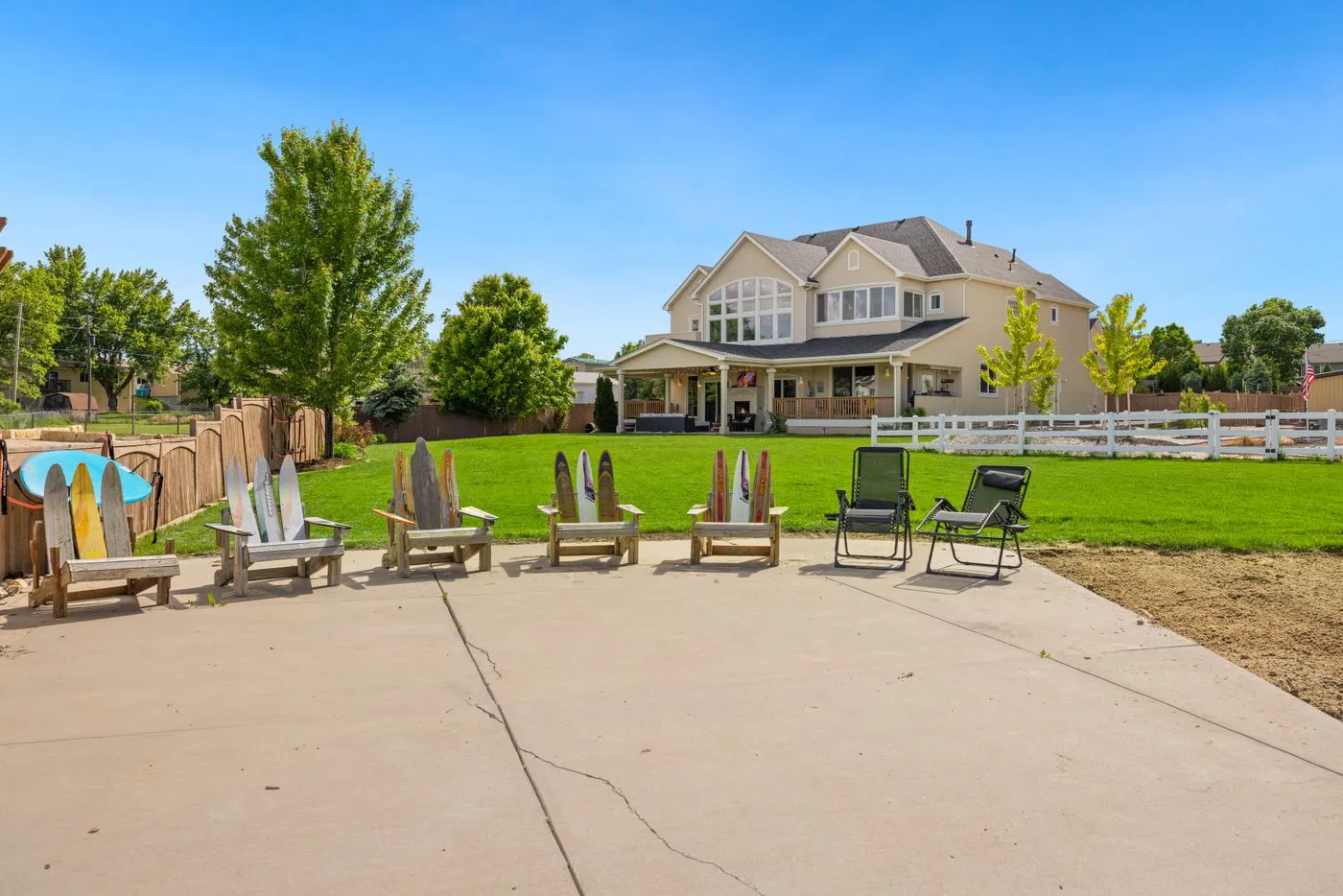A landscaped backyard patio with seating behind a two-story home