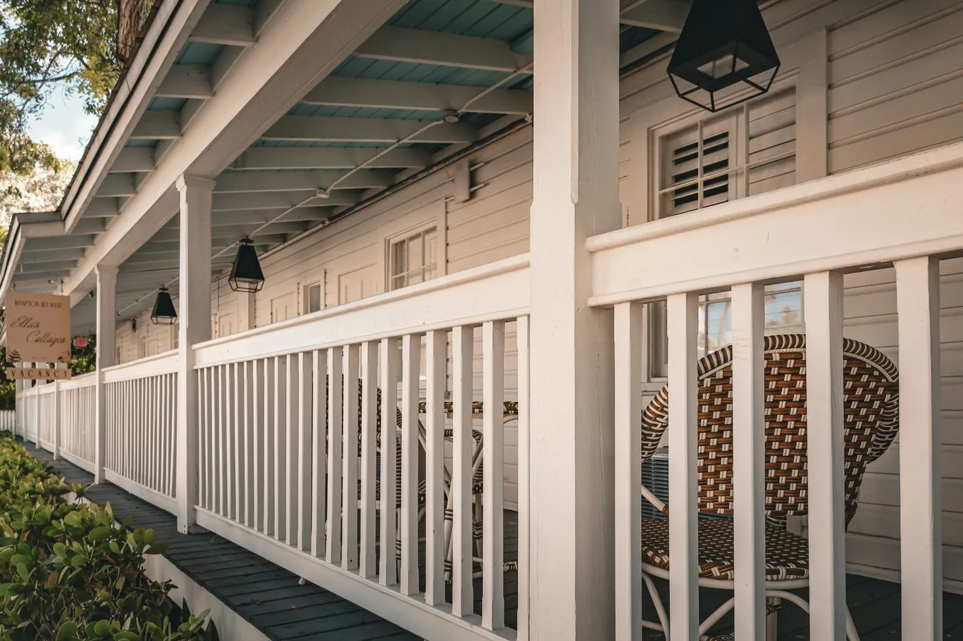 A covered porch with white railings and wicker seating